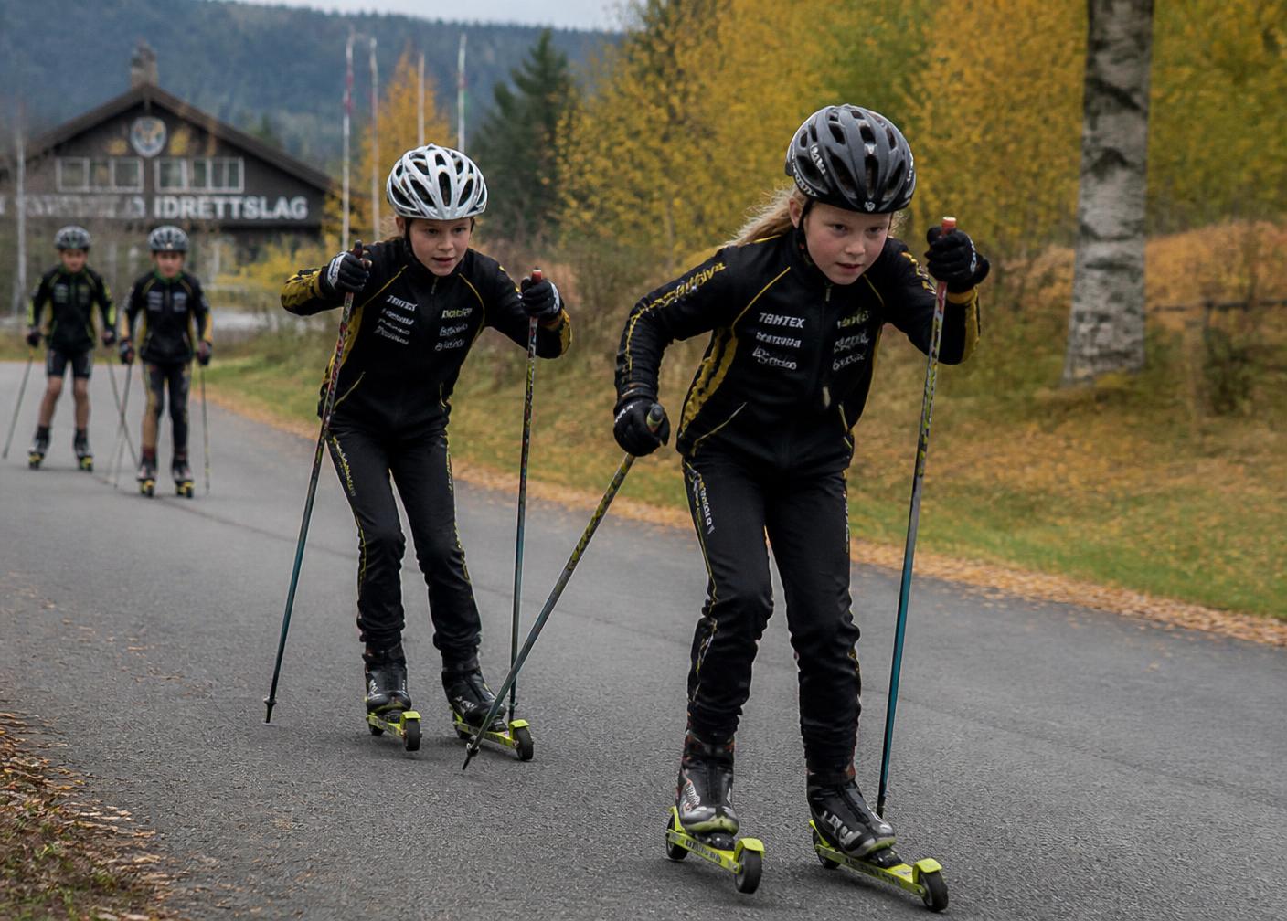 Barn på rulleski langs asfaltvei i norsk høstlandskap